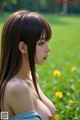 A woman with long brown hair standing in a field of flowers.