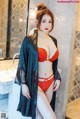 A woman in a red lingerie posing in a bathroom.