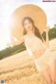 A woman in a straw hat standing in a field.