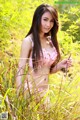 A woman in a pink bikini standing in tall grass.
