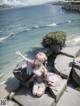 A girl sitting on a rock by the ocean.