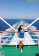 A woman standing on the deck of a cruise ship holding a bottle of orange juice.