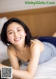 A woman laying on top of a bed smiling.