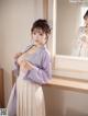 A woman in a purple kimono standing in front of a mirror.