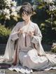 A woman in a white kimono sitting on the ground.