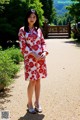 A woman in a red and white kimono standing on a dirt road.