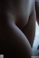 A close up of a naked woman's butt in the dark.